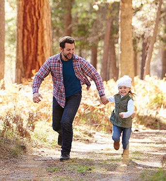 Father and daughter running in forest