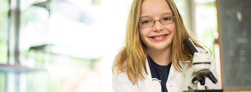 4-H girl in labcoat with microscope.