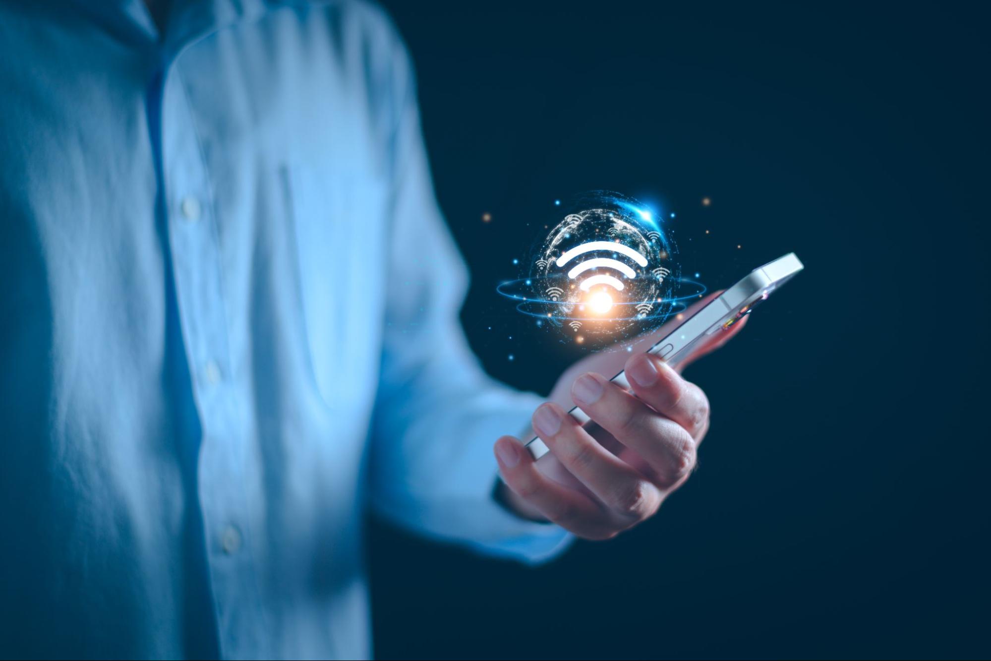 A person using their phone with a glowing wifi signal hovering above