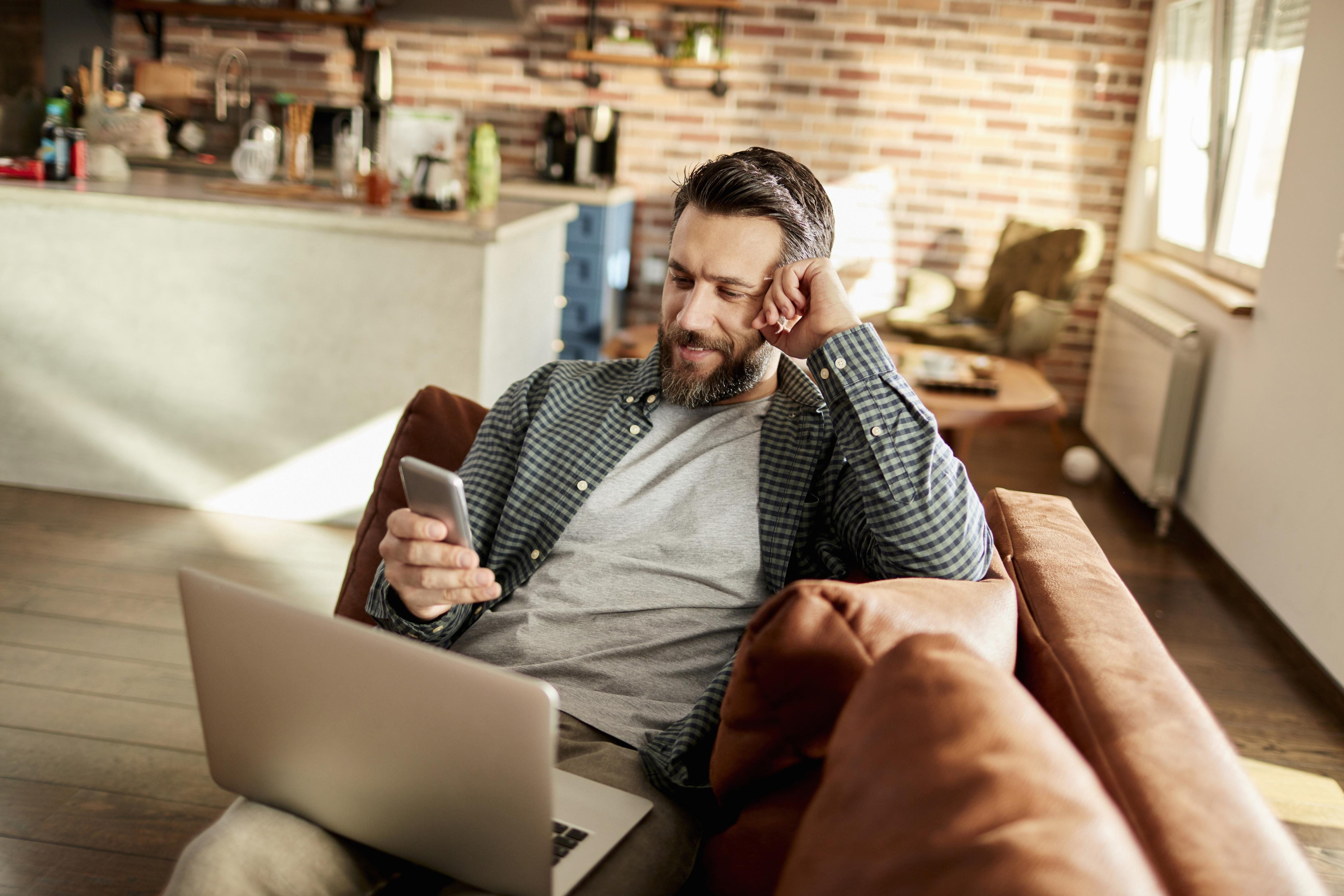 Man multitasking with a smartphone and laptop, while using satellite internet.