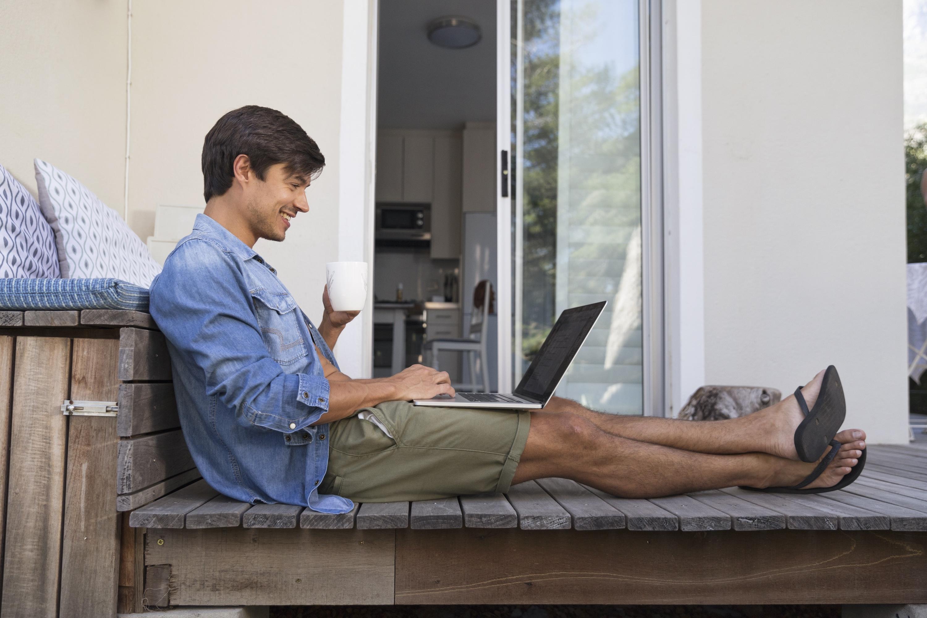 Man using a laptop on his deck, enjoying Whole Home Wi-Fi coverage.
