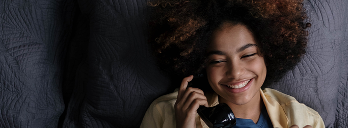 Smiling woman talking on the phone using Hughesnet Home Voice service through VoIP with her satellite connection.