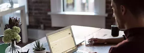 Man working on a laptop at home, relying on Hughesnet satellite internet for a seamless connection.