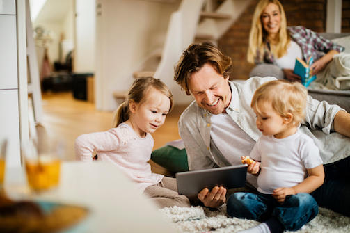 father looking at tablet with two young kids