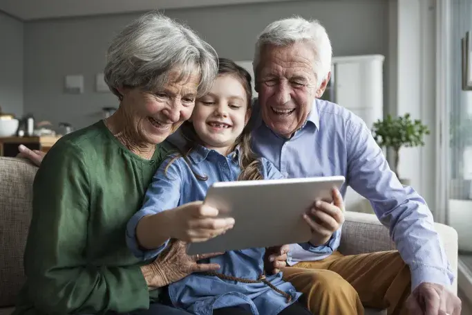 Elderly couple and granddaughter streaming on a tablet, using Hughesnet reliable satellite internet connection.