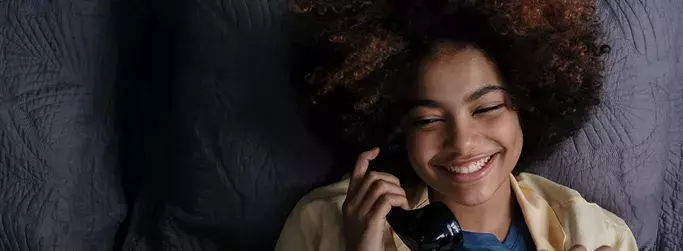 Smiling woman talking on the phone using Hughesnet Home Voice service through VoIP with her satellite connection.
