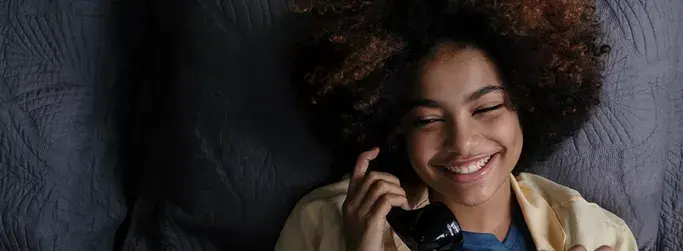 Smiling woman talking on the phone using Hughesnet Home Voice service through VoIP with her satellite connection.